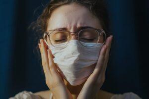 Worried woman wearing a protective face mask, expressing anxiety during a health crisis. Close-up portrait highlighting fear and concern during pandemic times