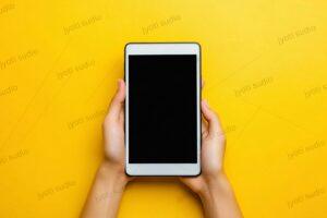 Hands Holding Tablet: Blank Black Screen, Yellow Background, Mobile Technology, Communication Device, Modern Gadget, Copy Space